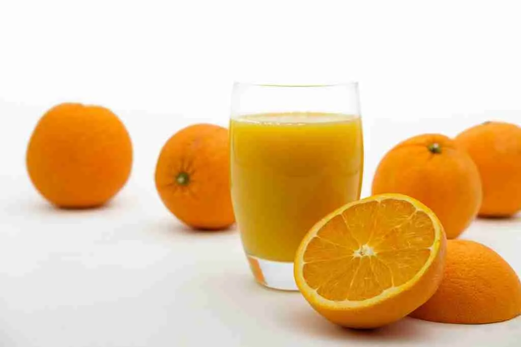 A glass of orange juice with its fruits that is healthy for guinea pigs