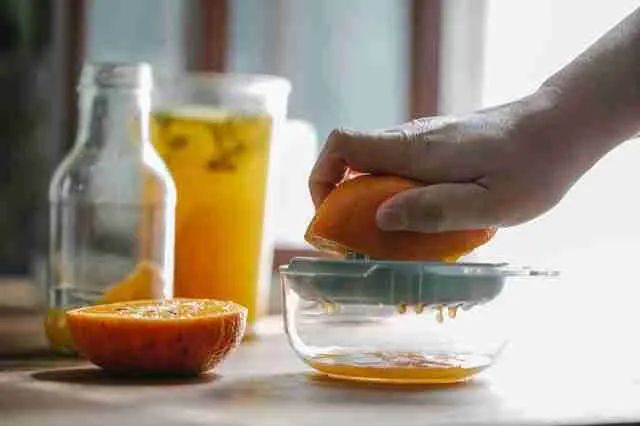 A person squeezing an orange juice 